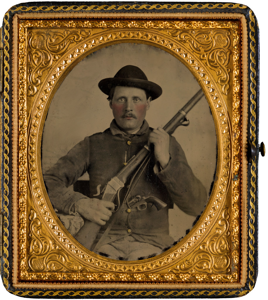 Unidentified soldier in Confederate uniform with Berdan's Sharps rifle and Colt 1862 Police Model pistol